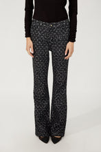 Load image into Gallery viewer, Model wearing black and silver abstract patterned pants, black top and black heels against a white background.