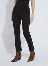 Load image into Gallery viewer, Model wearing black pants with bronze rhinestone accents and brown boots against a white background.