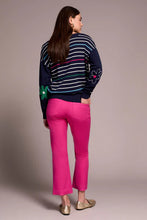 Load image into Gallery viewer, Woman wearing a navy sweater with colorful flower patterns, bright pink pants and metallic flats against a neutral background.