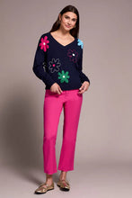 Load image into Gallery viewer, Woman wearing a navy sweater with colorful flower patterns, bright pink pants and metallic flats against a neutral background.
