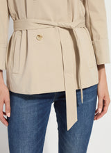 Load image into Gallery viewer, Close up of beige trench and blue jeans against a white background.