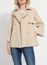 Load image into Gallery viewer, Woman wearing a beige trench and blue jeans against a white background.