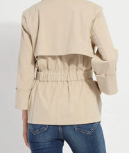 Load image into Gallery viewer, Close up of beige trench and blue jeans against a white background.