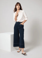 Load image into Gallery viewer, The Dion Sailor Palazzo Denim Pant is a chic sailor-inspired piece, perfect for modern fashion enthusiasts. This cropped wide-leg palazzo pant boasts trendy contrast-color topstitching and is crafted from premium 4-way stretch Knit Denim for comfort and flexibility. Featuring a clean front with a stylish waist seam, functional pockets adorned with metal buttons and eyelets, and back welt pockets, this design combines practicality with elegance.