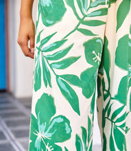 Load image into Gallery viewer, Green and cream floral and leaf patterned pants against a neutral background.