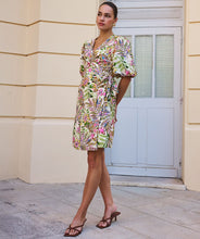 Load image into Gallery viewer, Woman wearing a colorful jungle print dress standing in front of a building entrance.