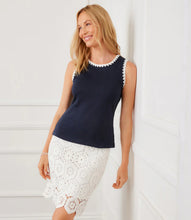 Load image into Gallery viewer, Woman wearing a navy sleeveless top with white crochet details and a white lace skirt against a white wall.