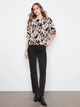 Load image into Gallery viewer, Woman wearing a black, brown and off-white cow print top, black jeans and black boots against a plain background.