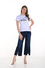 Load image into Gallery viewer, Woman wearing a white t-shirt with a graphic design, dark blue jeans and nude heels on a white background.