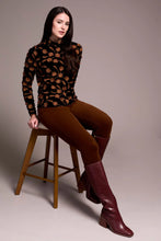 Load image into Gallery viewer, Woman sitting on a stool wearing a black velvet with tonal flowers top, brown pants with burgundy boots against a plain background.