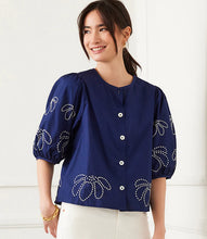 Load image into Gallery viewer, The Emely Embroidered Puff Sleeve Shirt by Karen Kane is a perfect blend of structured elegance and feminine charm. Featuring intricate white embroidery on a navy blue background, this stylish top adds a refined touch to any outfit. The puff sleeves create a statement look, while the pleated back detail enhances its flattering silhouette.