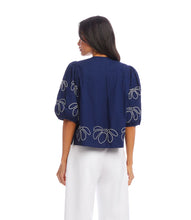 Load image into Gallery viewer, The Emely Embroidered Puff Sleeve Shirt by Karen Kane is a perfect blend of structured elegance and feminine charm. Featuring intricate white embroidery on a navy blue background, this stylish top adds a refined touch to any outfit. The puff sleeves create a statement look, while the pleated back detail enhances its flattering silhouette.