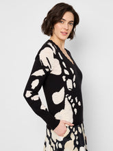 Load image into Gallery viewer, The Nic & Zoe Evie Evening Petal Sweater in Black Multi is a sophisticated pullover that combines elegance with comfort. Featuring a knit-in intarsia pattern, this sweater showcases a striking black-and-white design with scalloped neck trim for a feminine touch. The lightweight fabric ensures ease of wear, while the regular fit and long sleeves make it perfect for layering. Designed to sit at the hip, this sweater is versatile enough for both casual outings and dressier occasions.