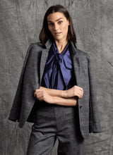 Load image into Gallery viewer, Woman wearing a plaid gray suit with a blue shirt posing against a grey background.