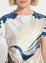Load image into Gallery viewer, Close-up of a model wearing a patterned top with blue and gold lines on a white background.