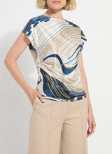 Load image into Gallery viewer, Woman wearing a patterned top and beige pants on a plain background.