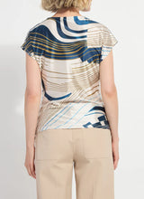 Load image into Gallery viewer, Woman wearing a patterned shirt with abstract design and beige pants on a plain background.