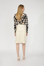 Load image into Gallery viewer, Woman wearing a patterned top, bone colored pencil skirt and tan heels against a white background.