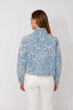 Load image into Gallery viewer, Woman wearing a blue and multi-color embroidered floral patterned jacket and white jeans against a white background.