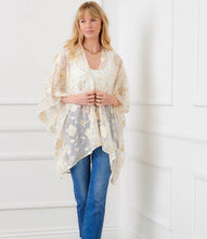Load image into Gallery viewer, Woman wearing a floral gold and off-white kimono over a white top and blue jeans, standing against a white wall.