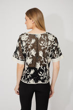 Load image into Gallery viewer, Woman wearing a sheer black embroidered floral patterned sequin short sleeve top and black pants against a white background.