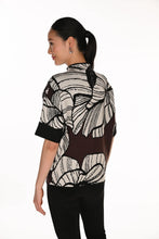 Load image into Gallery viewer, A woman with her back to the camera wearing a short-sleeve mock-neck knit sweater with a brown and off-white abstract floral pattern, paired with black pants, against a plain white background.