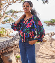 Load image into Gallery viewer, A vibrant floral print distinguishes this light-weight crepe top detailed with billowy blouson sleeves. A stunning top that will pair with a number of your favorite bottoms. Colors- Black, blue, pinks. Blouson sleeve. Split neck with ties. Floral print. Fabric -100% Rayon. Care- Dry clean.