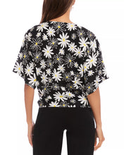 Load image into Gallery viewer, Woman wearing a black short sleeve tie top with white daisies and black pants on a white background.