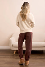 Load image into Gallery viewer, Woman wearing a moonstone sweater, brown pants and brown shoes standing in a room with a beige couch.