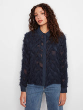 Load image into Gallery viewer, Woman modeling a navy blouse with fringe detailing and blue jeans against a white wall.