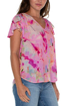 Load image into Gallery viewer, This woven tee is the perfect blouse to take you from season to season. Featuring a shirred back, v-neckline, and flirty petal sleeves, this top is a standout in vibrant colors.! Drawstring details at the shoulders create a fun and modern look.