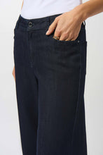 Load image into Gallery viewer, Closeup of a woman wearing a white top and dark denim blue wide leg jeans against a white background.