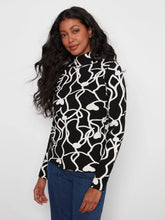 Load image into Gallery viewer, A woman modeling a black and white abstract wavy pattern mock neck sweater with blue jeans, set against a plain light gray background.