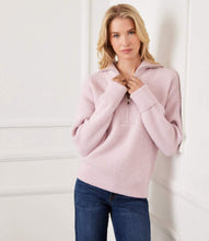 Load image into Gallery viewer, Woman wearing a zip front pink sweater and blue jeans against a white wall.