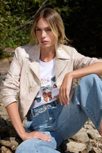 Load image into Gallery viewer, Woman sitting outdoors wearing a pink and gold metallic moto jacket, white t-shirt with butterfly design, and blue jeans.