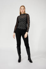 Load image into Gallery viewer, Woman wearing a black patterned top, black pants and black boots against a white background.