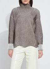 Load image into Gallery viewer, Model wearing a striped sweater and white pants against a plain background.