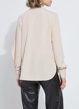 Load image into Gallery viewer, Model wearing a rose petal colored blouse with ruffle detailing and black pants against a white background.