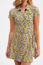 Load image into Gallery viewer, A woman wearing a short-sleeve collared shirt dress with a yellow, black, and white abstract print, shown against a plain light gray studio background.