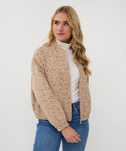 Load image into Gallery viewer, Woman wearing a beige knitted jacket over a white turtleneck with blue jeans against a white background.