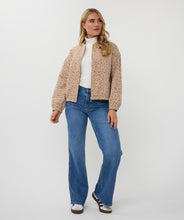 Load image into Gallery viewer, Woman wearing a beige bomber jacket, white shirt, blue jeans, and black and white shoes against a white background.