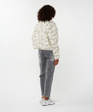 Load image into Gallery viewer, Woman wearing an off-white and silver sequin bomber jacket over a white top, grey jeans and white sneakers against a white background.