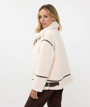 Load image into Gallery viewer, The luxurious Faux Fur Aviator Jacket in creamy ivory is a fashion statement. It boasts a plush faux fur exterior, complemented by dark brown leather accents and an elegant buckle detail for extra style. The inside is made of velvety suede that adds extra warmth. Designed with long sleeves and a zip-up closure, it's not only chic but also practical, ensuring warmth and fashion throughout the cooler seasons.