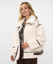 Load image into Gallery viewer, The luxurious Faux Fur Aviator Jacket in creamy ivory is a fashion statement. It boasts a plush faux fur exterior, complemented by dark brown leather accents and an elegant buckle detail for extra style. The inside is made of velvety suede that adds extra warmth. Designed with long sleeves and a zip-up closure, it's not only chic but also practical, ensuring warmth and fashion throughout the cooler seasons.