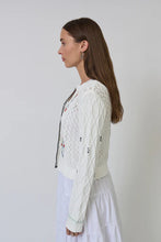 Load image into Gallery viewer, Woman wearing a white and multicolor knit cardigan and white skirt against a plain background.