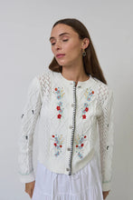 Load image into Gallery viewer, Woman wearing a white embroidered cardigan and white skirt against a plain background.