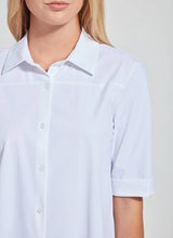 Load image into Gallery viewer, A close-up of a woman wearing a white short-sleeve button-up shirt with a pointed collar and rolled cuffs, shown against a light neutral background.