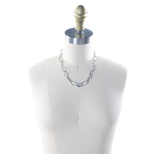 Load image into Gallery viewer, Elevate your jewelry collection with the Karisma Tennis Necklace, a statement piece designed to captivate. Featuring open metallic links that create an airy, lightweight feel, this necklace ensures effortless elegance. At its center, a dazzling crystal steals the spotlight, catching and reflecting light for a brilliant, eye-catching shimmer.