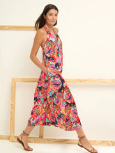 Load image into Gallery viewer, Woman wearing a bright red multicolor sleeveless dress and sandals in a white room with wooden frames.