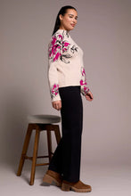 Load image into Gallery viewer, Woman wearing a pink and black floral sweater, black pants and brown boots standing next to a wooden stool against a plain background.